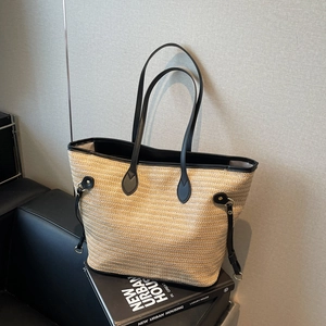 Minimalist straw tote bag with black leather trim and long handles for urban commute