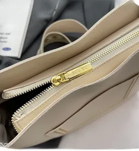 Macro shot of smooth gold zipper detail with SOUKU logo on beige leather tote bag