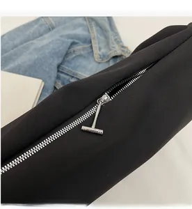 Close-up of smooth silver T-shaped metal zipper on black canvas tote bag with dense teeth