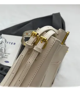 Macro detail of high-quality light gold buckle and leather stitching on beige bucket bag