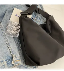 Detail of minimalist black nylon crescent bag on denim background with soft texture
