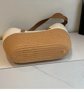 Detail of two-tone woven straw shoulder bag with durable stitching and leather strap