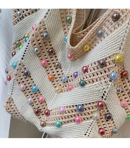 Detail of hand-woven beige tote bag with colorful pearls and textured knit pattern