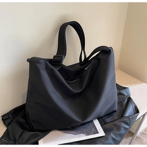 Close-up of a large black soft fabric tote bag with an adjustable wide shoulder strap
