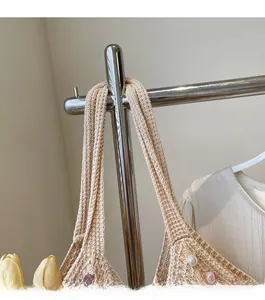 Detail of woven shoulder strap on a beige crochet beach bag with pearl and bead accents