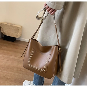 Detail of a brown bucket bag showing geometric jacquard strap and white dot accents