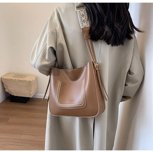 Brown leather bucket bag detail with U-shaped pocket and jacquard woven strap