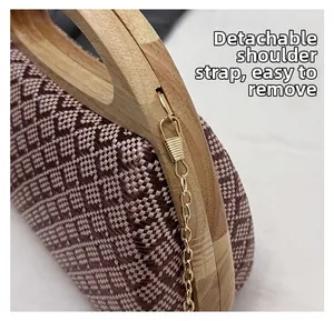 Close-up of the detachable gold chain strap and wooden handle on the woven clutch bag