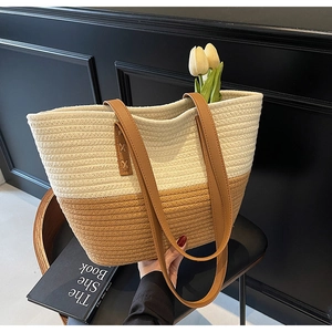 Detail of the high-capacity woven tote bag with contrast stitching and leather handles