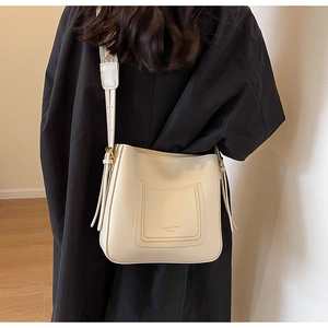 Detail of minimalist cream bucket bag with decorative pocket and woven strap detail