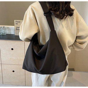 Close-up of a large black soft leather tote bag showing smooth matte texture and wide strap