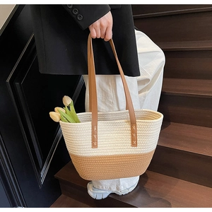 Detail of the dual-tone woven tote bag featuring reinforced brown leather handles and texture