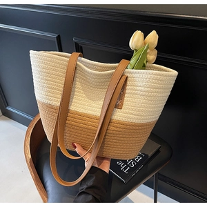 Close-up of woven tote bag with ivory and brown contrast paneling and leather straps