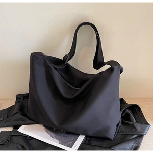 Close-up of black nylon tote bag on leather jacket showcasing durable fabric texture