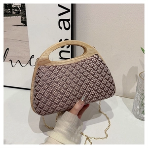 Detail of woven straw clutch with wooden handle and gold chain strap for evening events