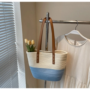 Detail of woven contrast tote bag with leather straps and tulip decor hanging on rack
