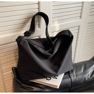 Detailed shot of the black nylon tote bag showing its lightweight texture and wide strap