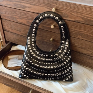 Schwarze glänzende Ledertasche mit modischen Silbernieten in geschwungenem Muster