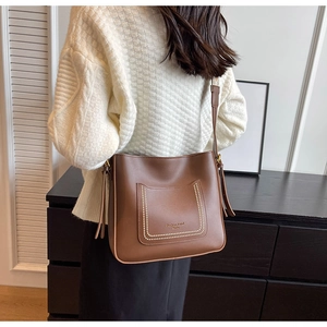 Side view of a vintage brown leather bucket bag on a model showing stitching and drawstrings