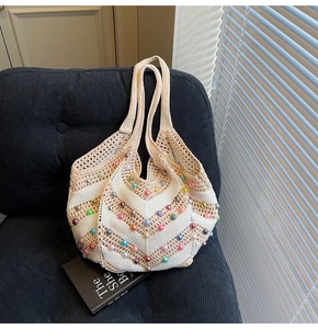 Detail of hand-woven beige tote bag with colorful faux pearls on striped fabric surface