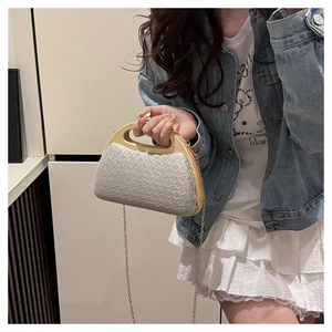 Detail of woven clutch bag with natural wood handle and elegant gold chain strap