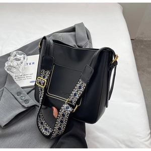 Detail of black PU leather bucket bag featuring a vintage geometric jacquard strap