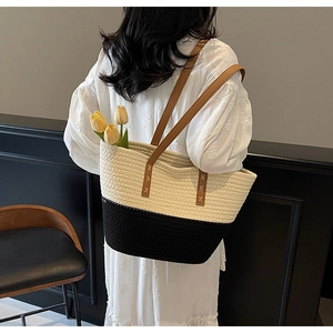 Detail of bohemian woven tote bag with brown leather handles and stitched cross patterns