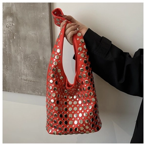 Détail d'un sac seau en cuir rouge orné de rivets métalliques argentés et de clous décoratifs