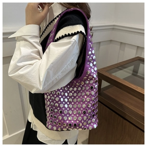 Détail d'un sac à main violet avec œillets métalliques et rivets sur la bandoulière