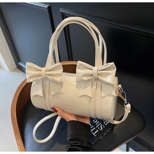 Detail of white glossy cylindrical bag featuring large bows and reinforced top handles