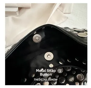 Détail de la boucle magnétique argentée et des rivets sur le sac seau noir