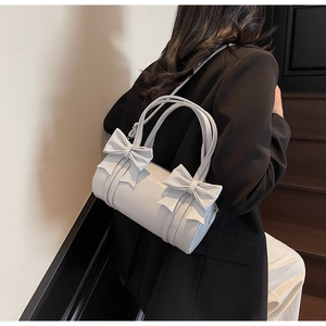 Side view of light blue-grey cylinder bowling bag with bow details on female model