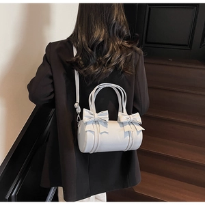 Detail view of cream white pillow bag featuring distinctive 3D leather bow accents