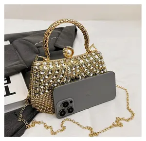 Detail view of rhinestone evening bag with pearl clasp and chain strap next to a smartphone