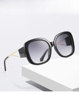 Close-up of oversized square sunglasses with black frames and gold metal temple details