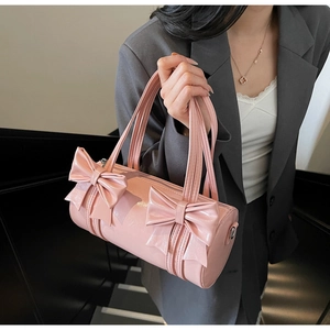 Detailed shot of pink patent leather cylinder bag with two large decorative bows