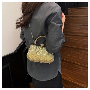 Detail of gold evening clutch bag with sparkling rhinestones, tassels and pearl clasp