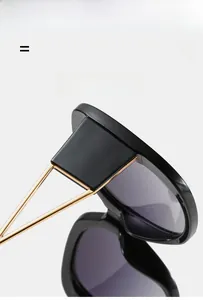 Detail of black oversized square sunglasses featuring gold hollow triangle metal temples