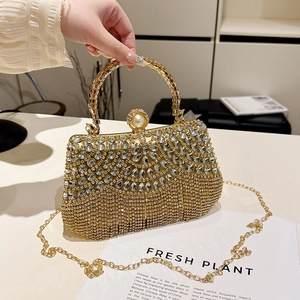 Detail of gold luxury evening clutch with tassel rhinestones and pearl clasp