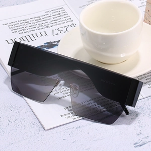 Oversized flat top shield sunglasses with black lenses on magazine and ceramic cup