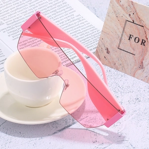 Pink oversized rimless one-piece sunglasses in a stylish flat-lay fashion setting