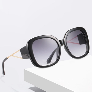 Oversized square sunglasses with black frames and gold temples on white blocks