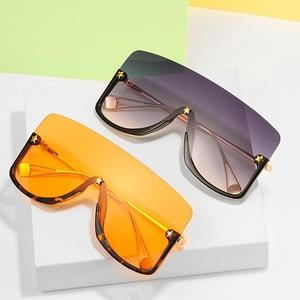 Oversized shield sunglasses with star rivets and gradient lenses on a display stand
