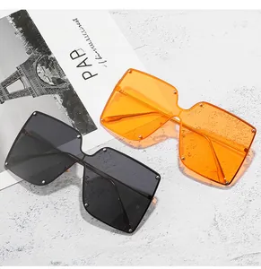 Detail of oversized square sunglasses with silver rivet studs in black and orange tints