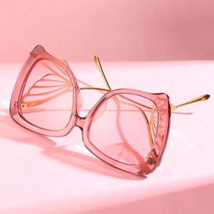 Lunettes de soleil papillon roses avec branches en métal doré sur fond rose doux