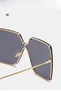 Detail view of gold metal hinges and decorative rivets on oversized square sunglasses