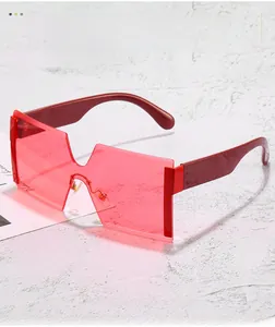 Detail view of red frameless oversized sunglasses with wide burgundy temples on stone