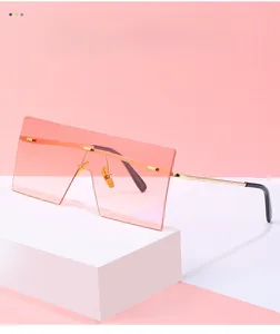 Detail of square rimless sunglasses featuring gradient pink-orange lenses and gold metal frame