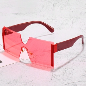 Fashion oversized rimless sunglasses with red transparent lenses on marble surface