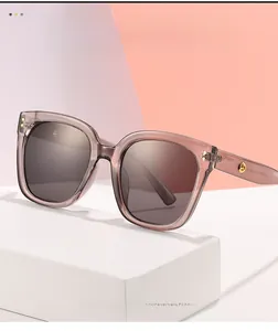 Detail of oversized tea brown sunglasses with a golden metal logo on the temple